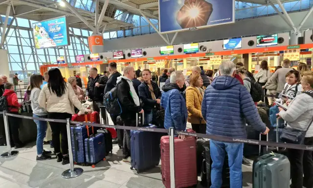 Kolejka do odprawy na jednym z największych lotnisk w Polsce. Pasażerowie z bagażami czekają na swoją kolej.