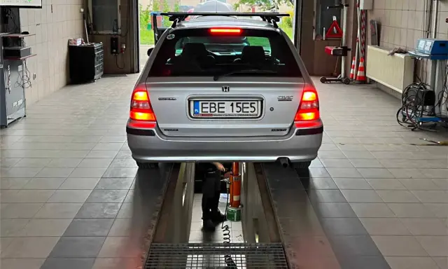 Srebrny kombi Honda Civic na podnośniku w warsztacie. Zastanawiasz się, ile kosztuje przerejestrowanie samochodu?