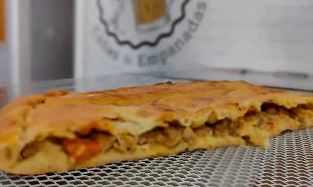 Empanada dorada rellena de carne y verduras. Perfecta para acompañar con una ensalada fresca o una salsa picante.