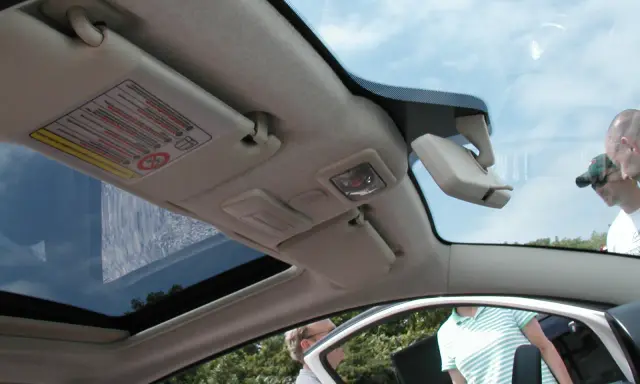 Interior de un Fiat 500 con el techo solar abierto, mostrando el parasol y el espejo retrovisor.