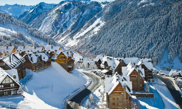 Pueblo nevado en los Pirineos, ideal para saber donde ir en el puente de diciembre. Casas de piedra y madera cubiertas de nieve, rodeadas de bosques y montañas.