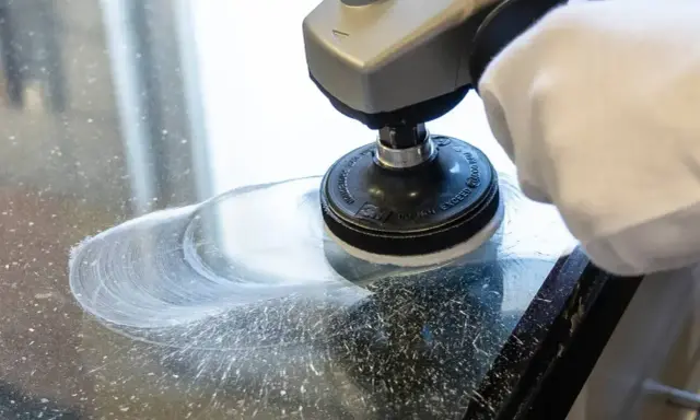 Rękawica i polerka usuwają resztki starego silikonu z szyby.