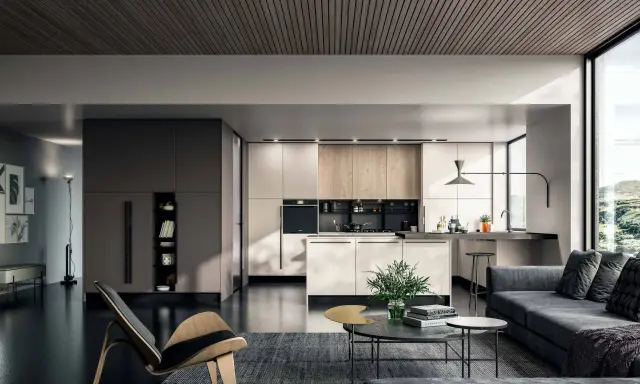 Un elegante appartamento open space moderno con cucina a vista, zona living con divano grigio e poltrona di design.