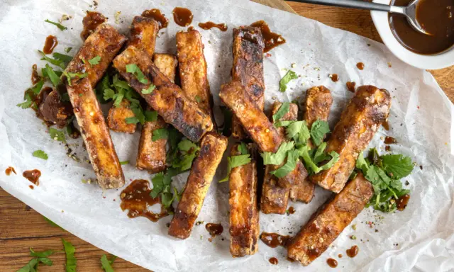 Marinierter Tofu, knusprig gebraten und mit einer dunklen Sauce beträufelt, garniert mit frischem Koriander. Perfekt zum Dippen!