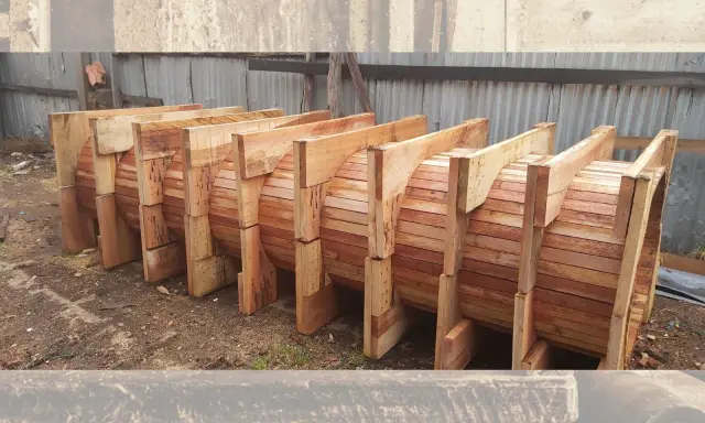 Encofrados de madera apilados, listos para dar forma a grandes estructuras circulares.