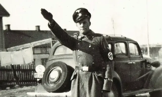 En man i uniform med hakkors hälsar. Bilden visar svenska nazister.