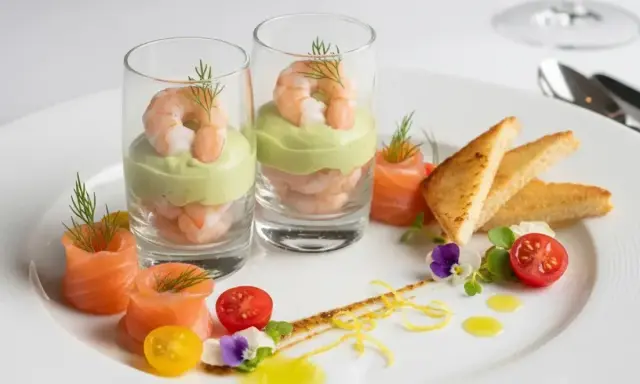 Recette entrée froide gastronomique facile : crevettes et avocat en verrine, saumon fumé roulé, toasts grillés, tomates cerises et fleurs comestibles.
