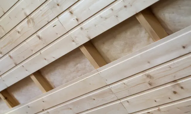 Pose de lambris en bois clair, montrant la structure sous-jacente et l'isolant.