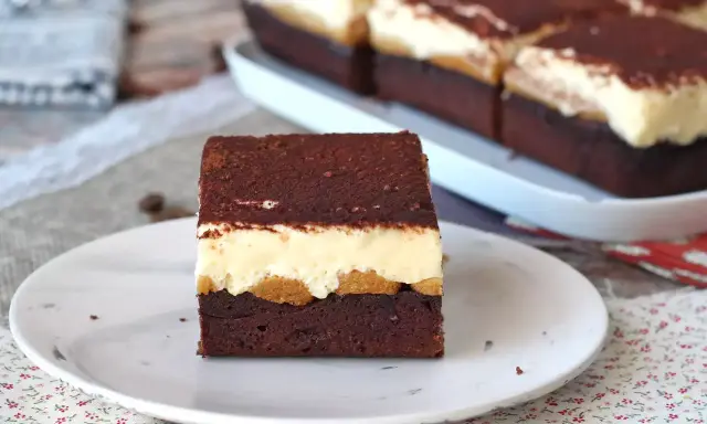 Pyszny deser tiramisu przepis. Warstwy czekoladowego ciasta, biszkoptów i kremu, posypane kakao.