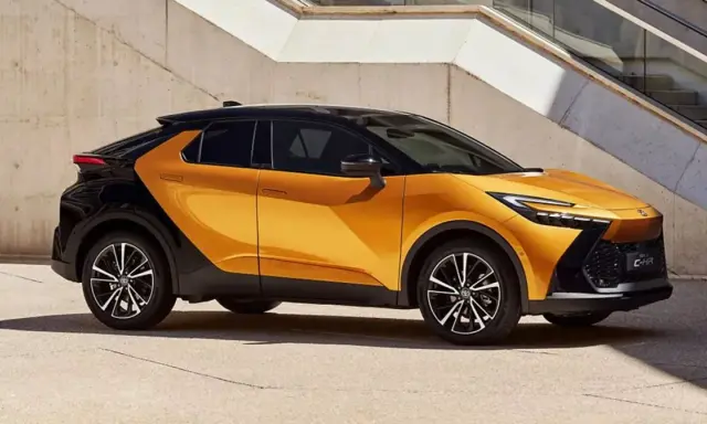 Nowy Toyota C-HR GR w kolorze pomarańczowo-czarnym, z dynamiczną linią nadwozia, zaparkowany przy betonowej ścianie.