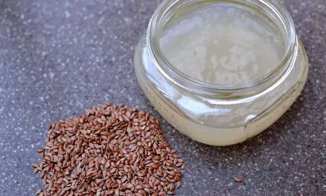 Graine de lin pour rajeunir : une poignée de graines de lin brunes à côté d'un pot en verre rempli d'un gel clair, peut-être un sérum fait maison.