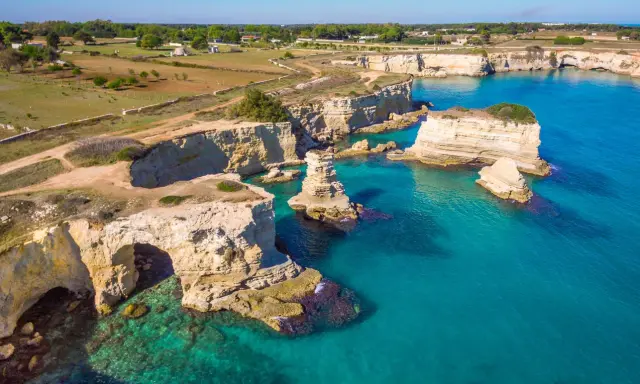 Scogliere bianche e mare turchese in una splendida **Puglia estate**. Faraglioni emergono dall'acqua cristallina, un vero paradiso.