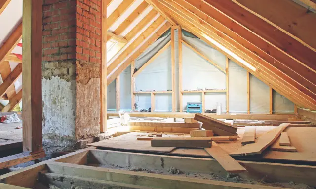 Aménagement des combles : début de la création d'un plancher avec des poutres en bois et des matériaux de construction.