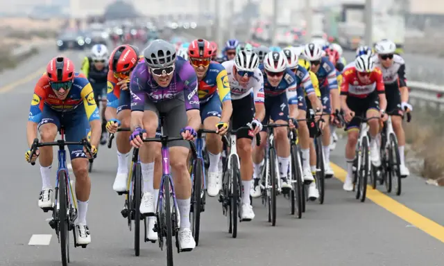 Max Walscheid im violetten Trikot kämpft sich mit anderen Radfahrern durch ein Rennen.