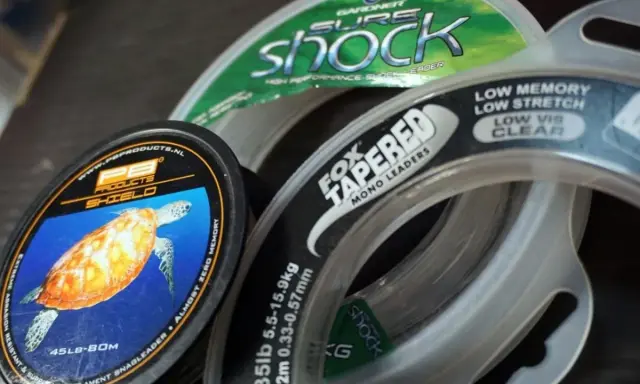 Wybór między żyłką a plecionką to kluczowa decyzja wędkarza. Na zdjęciu widać różne rodzaje żyłek, w tym PB Products Shield i Fox Tapered Mono Leaders.