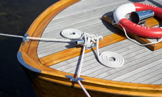 Détail d'une peinture de bateau en bois, avec cordages blancs et une bouée de sauvetage rouge et blanche.