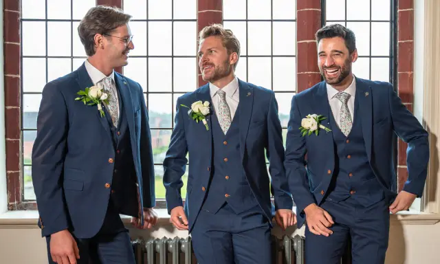 Three groomsmen in navy suits with floral ties and boutonnieres, ready for the usher wedding.