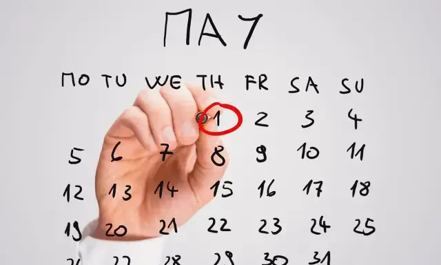 Ręka zakreśla czerwonym pisakiem datę 1 maja na kalendarzu. To ważne awizo, początek miesiąca.