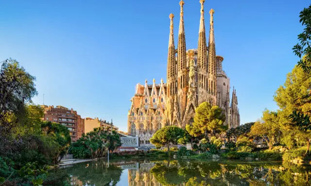 La Sagrada Familia, simbolo di **attività Barcellona**, si specchia in un laghetto circondato da verde.