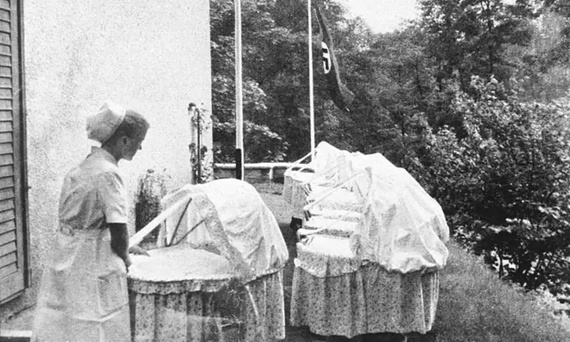Pielęgniarka przy wózkach dziecięcych. Flaga nazistowska w tle. To obrazek z czasów Lebensborn, co to za program?