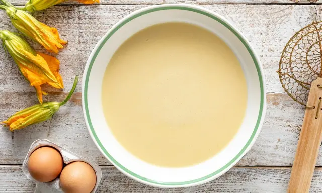 Pastella per fiori di zucca pronta in ciotola, con fiori freschi e uova a lato.