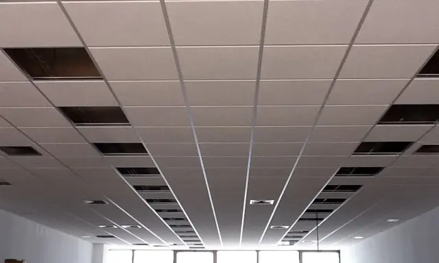 Instalación de un falso techo modular con paneles blancos y perfiles metálicos. Se aprecian huecos para iluminación o ventilación.