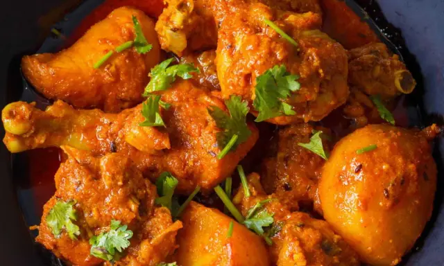 Un plat appétissant de poulet et de pommes de terre en sauce curry, garni de coriandre fraîche. Un délice pour les amateurs de marinade poulet curry.