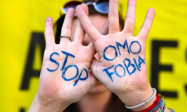 Mani con scritto "STOP OMOSESSUALITÀ" in blu, un messaggio contro il bullismo omofobico.