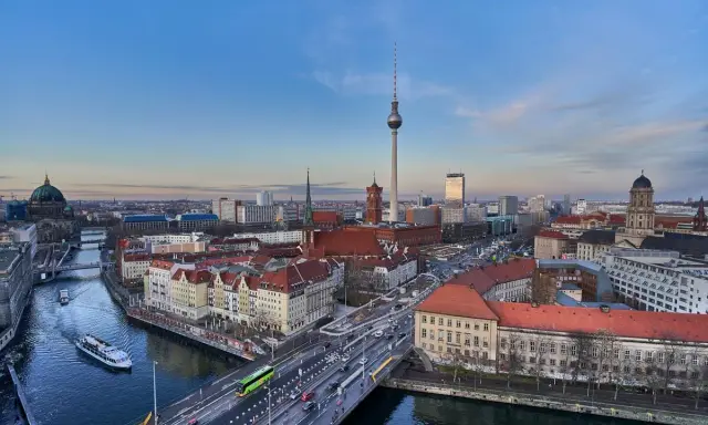 Ampio panorama berlino con la Torre della Televisione, il Duomo e il fiume Sprea. Traffico e barche animano la scena urbana.