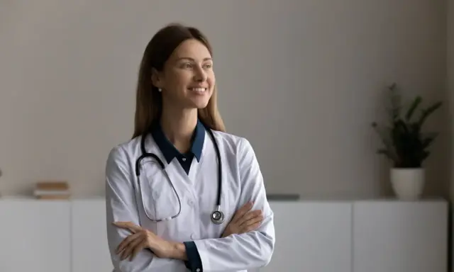 Une podologue souriante, avec un stéthoscope autour du cou, réfléchit à la rédaction d'une lettre pour le médecin traitant.