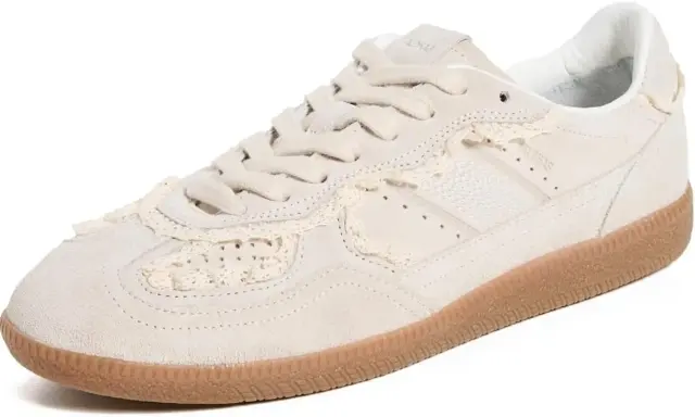 Zapatilla deportiva de ante color crema con detalles de encaje a crochet y suela de goma.