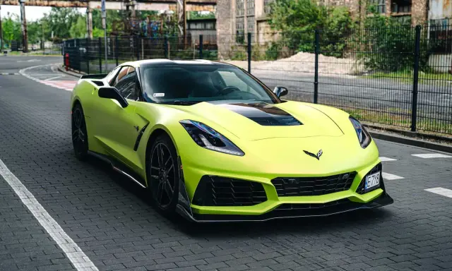 Jasnozielony Chevrolet Corvette C7 na brukowanej drodze. Zastanawiasz się nad corvette c7 cena?