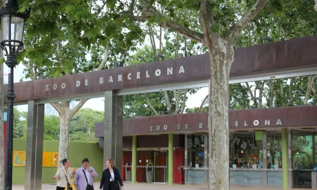 Eingang zum Zoo de Barcelona mit drei Frauen, die davor spazieren gehen.