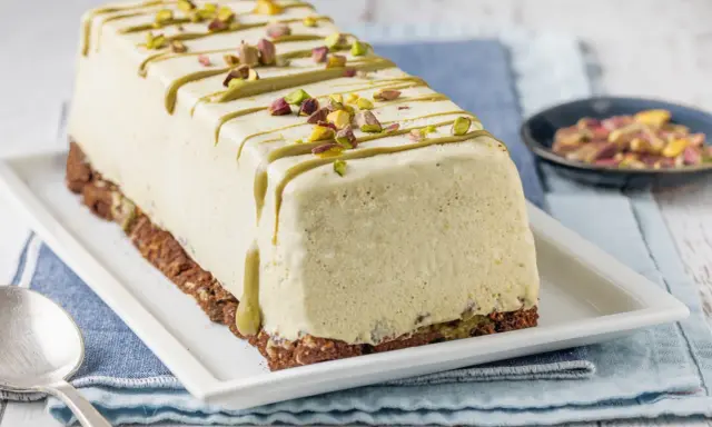 Semifreddo al pistacchio decorato con glassa verde e granella di pistacchi, su base croccante.