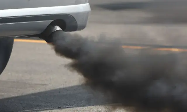 El tubo de escape de un coche emite una densa nube de humo negro al acelerar, contaminando el aire.