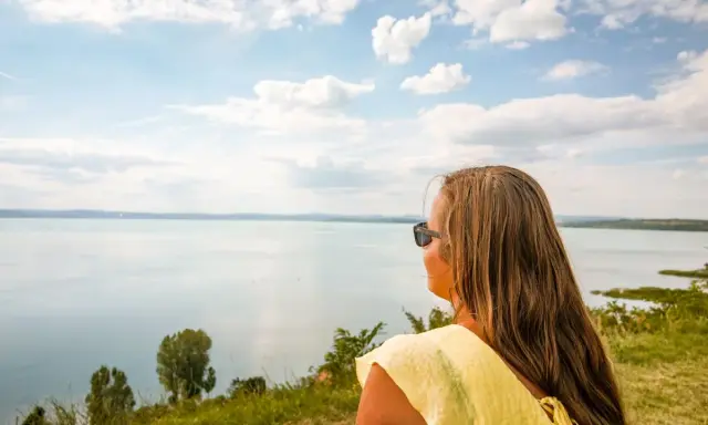 Kobieta w żółtej bluzce podziwia rozległy krajobraz nad Balatonem. To idealne miejsce na odkrywanie atrakcji i relaks.
