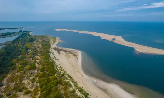 Piękny **urlop w Polsce** nad morzem. Piaszczysta plaża, zieleń i błękit wody tworzą malowniczy krajobraz.
