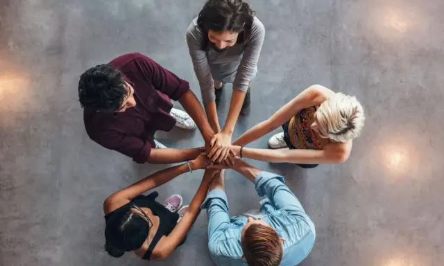 Un gruppo di persone unisce le mani, un'immagine che incarna la social definizione di unità e collaborazione.