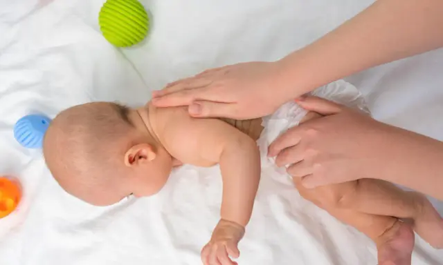Dziecko na brzuchu ćwiczy mięśnie. Brak tych ćwiczeń może mieć konsekwencje dla rozwoju. Zabawki obok.