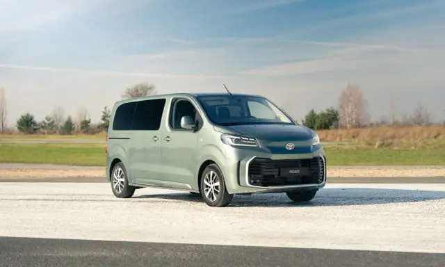 Nowy, zielony minivan Toyota Proace Verso na tle nieba i pól. Idealny na rodzinne wycieczki.