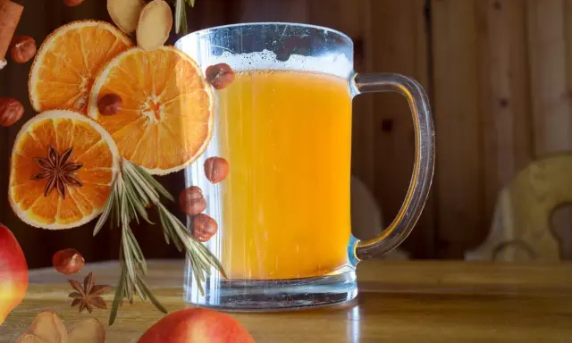 Szklanka piwnego grzańca z pomarańczą, anyżem, orzechami i rozmarynem.