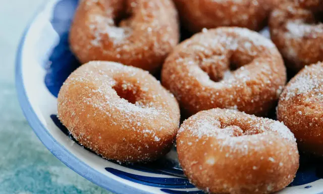 Rosquillas caseras de toda la vida, doradas y espolvoreadas con azúcar, listas para disfrutar.