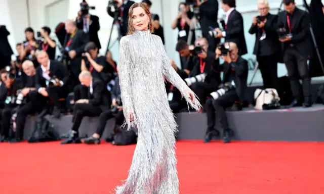 Isabelle Huppert, éblouissante dans sa robe argentée à franges, foule le tapis rouge de la mostra de Venise, sous le regard des photographes.