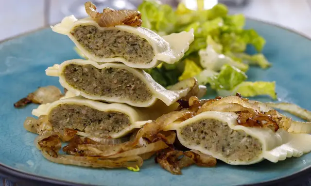 Gestapelte Maultaschen mit gebratenen Zwiebeln und Salat. Ein köstliches Maultaschen Rezept, das Appetit macht.