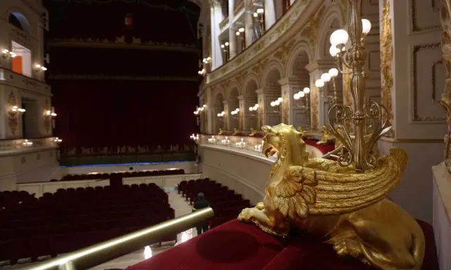 Interno del Teatro Galli di Rimini, con poltrone rosse, palchi dorati e una sfinge alata in primo piano.