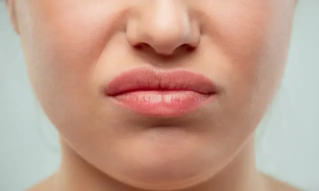 Gros plan sur une bouche pincée, le nez rouge que faire ? Une expression de dégoût ou de gêne.