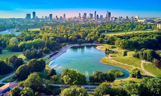 Piękny park z jeziorem i fontannami, idealne miejsce na relaks. W tle widać panoramę Warszawy, co czyni to jedno z fajnych miejsc w Warszawie.