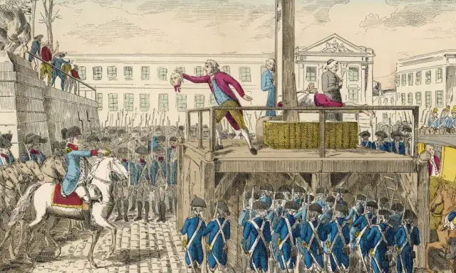 Ein Mann hält einen Kopf hoch, während die Guillotine in Frankreich bereitsteht. Soldaten und eine Menge beobachten die Hinrichtung.