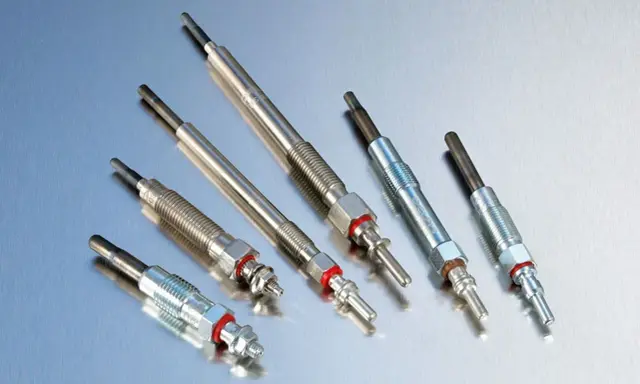 Sześć świec żarowych, kluczowych elementów silnika diesla, leży na metalicznej powierzchni.