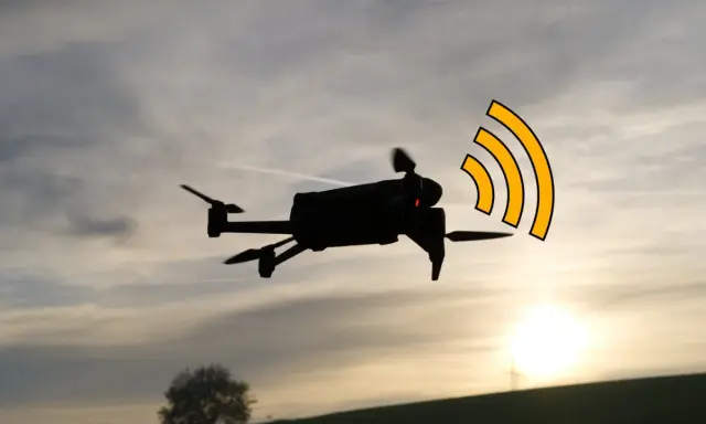 Drohne im Flug mit leuchtenden roten Lichtern und einer stilisierten DJI Antenne, die ein Funksignal aussendet.